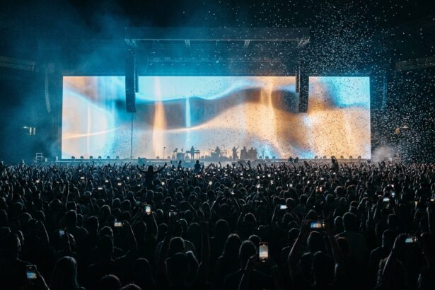 Konsertpublik på en arena med en jättelik videoskärm som lyser ovanför scenen